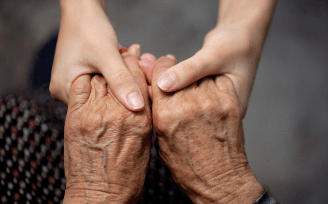 Die Hände einer jungen Person halten die Hände einer alten Person.