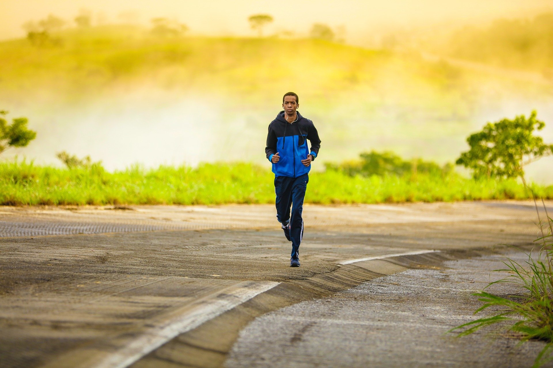 Ein junger Mann der joggt. Er trägt dabei eine blaue Sportjacke.