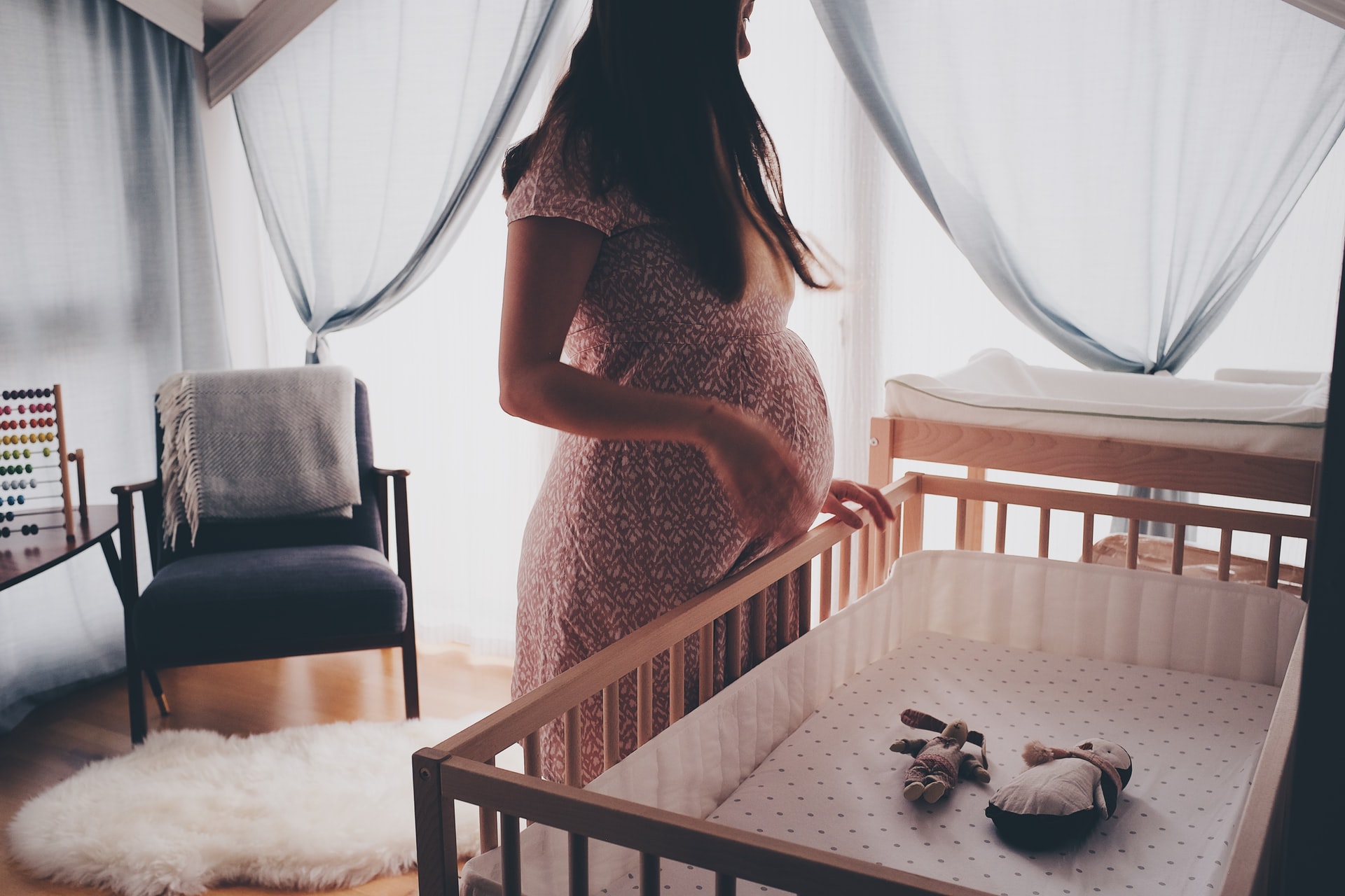 Angst vor der Geburt - Auf dem Bild sieht man eine werdende Mutter vor einem Kinderbettchen stehen - apomio.de Gesundheitsblog