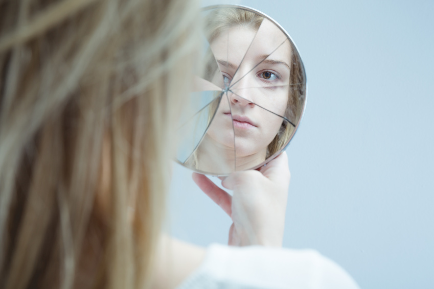 Ein Mädchen sieht in einen zerbrochenen Spiegel