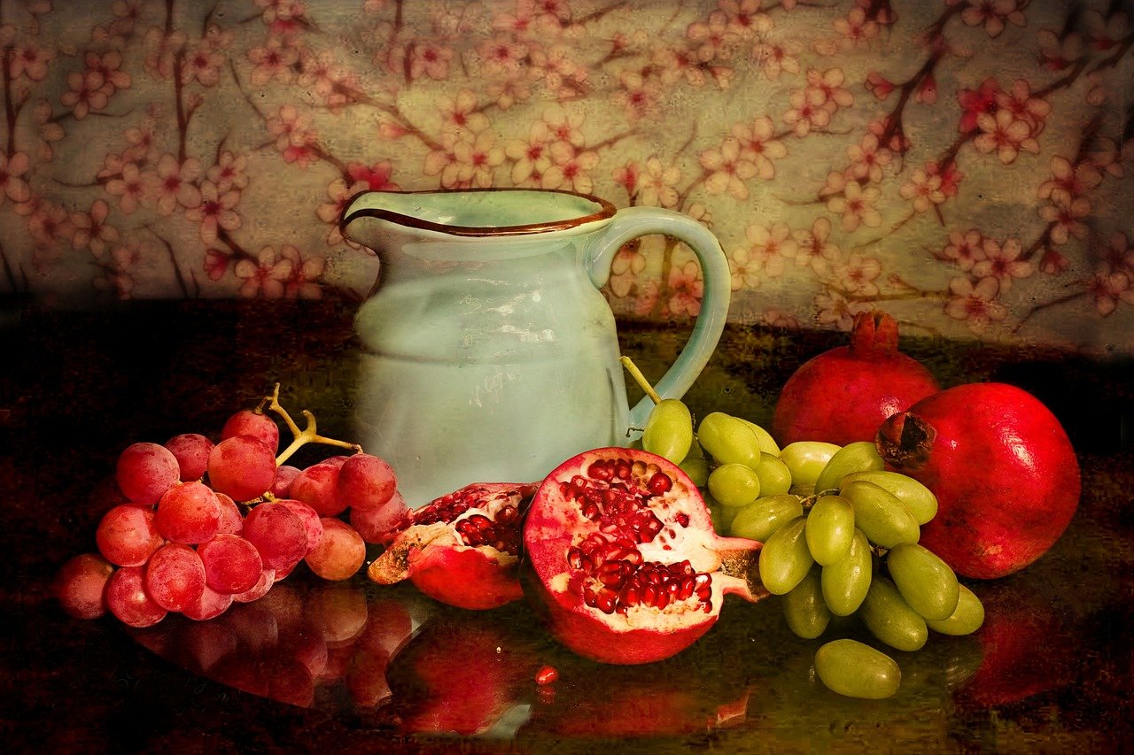 Nahrungsmittelunverträglichkeiten - Auf dem Bild sind Trauben, Granatäpfel und eine Kanne zu sehen.