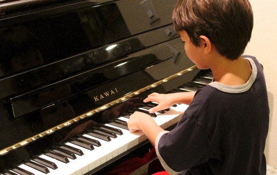 Kleiner Junge spielt Klavier.