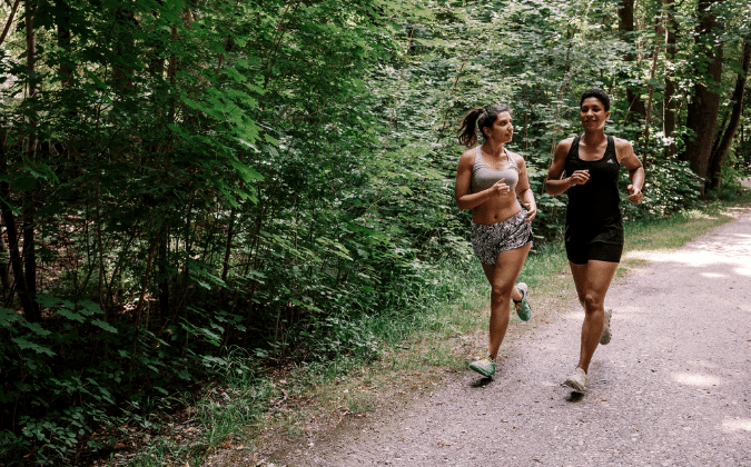 Zwei Freundinnen joggen gemeinsam im Wald