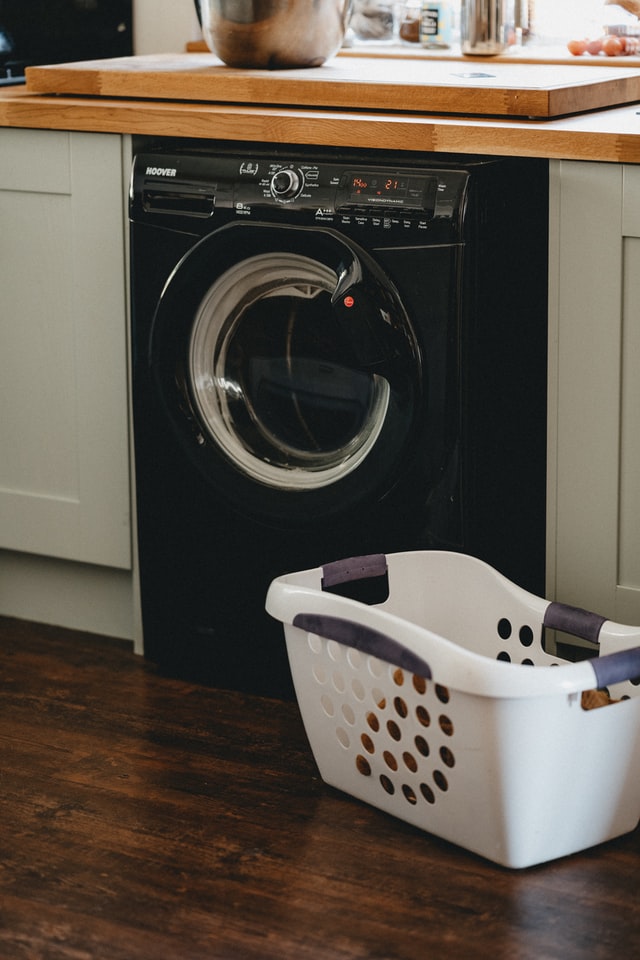 Hygienewaschmittel: sinnvoll, notwendig oder überflüssig? - Auf dem Bild ist eine schwarze Waschmaschine und ein weißer Wäschekorb zu sehen.
